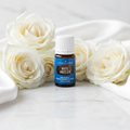 Young Living White Angelica oil bottle with white roses on marble spa setting