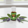 Stress Away essential oil on marble surface with green leaves and lavender