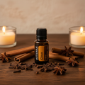 doTERRA Clove Essential Oil on rustic wood with whole cloves, cinnamon sticks and candlelight