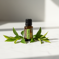 doTERRA Tea Tree Essential Oil on marble with green leaves