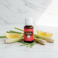 Lemongrass essential oil on marble with fresh lemongrass stalks and lemon slices