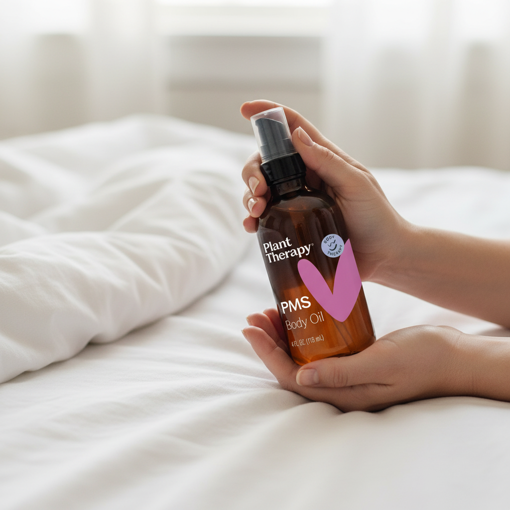 Hands holding Plant Therapy PMS Body Oil in cozy bedroom setting
