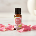 Edens Garden Rose Essential Oil on marble with fresh pink rose petals