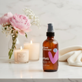 Plant Therapy PMS Body Oil on marble spa countertop with pink flowers and candles