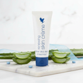Forever Renewing Skin Crème tube on white marble with aloe vera leaves