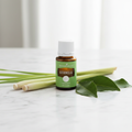 Citronella essential oil on marble with fresh lemongrass stalks and citronella leaves