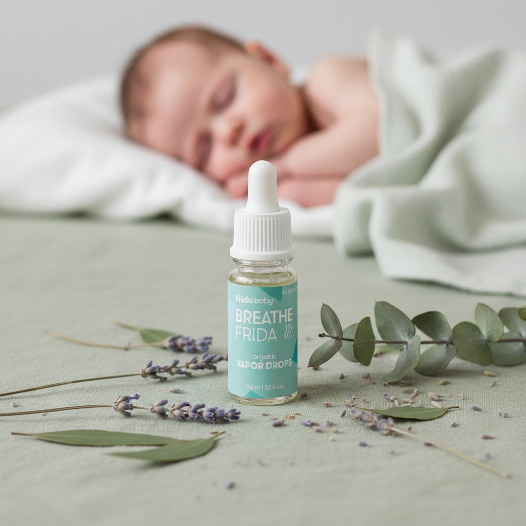 Frida Baby Vapor Drops on sage linen with sleeping baby in background