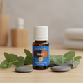 PanAway 15ml bottle on wood surface with eucalyptus and stones